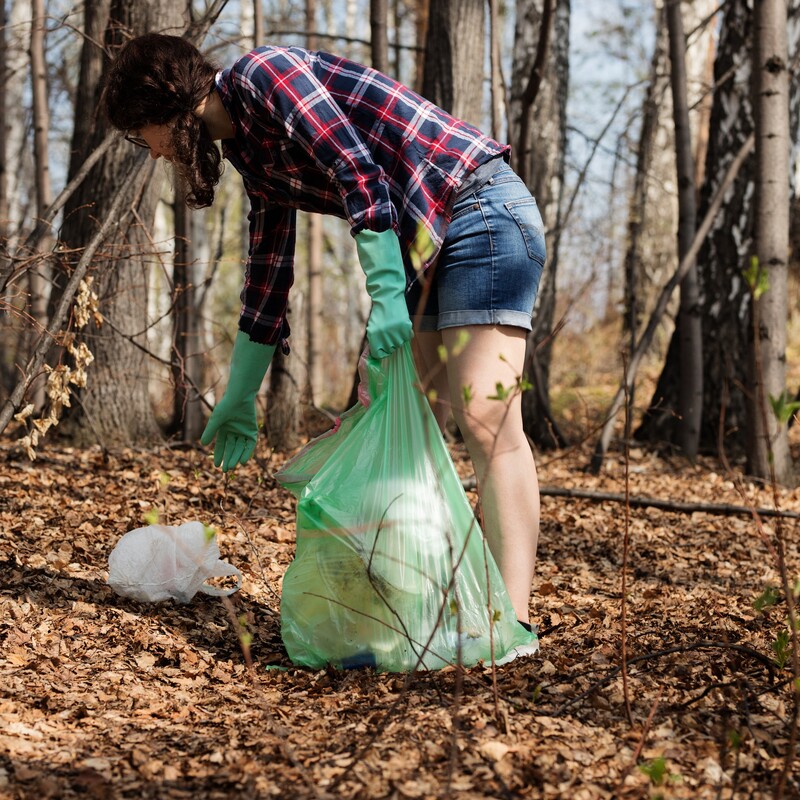 Frau sammelt Müll im Wald ein
