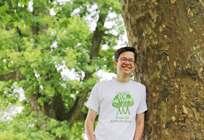 Mitarbeiter von Planet for the planet lehnt an den Baum