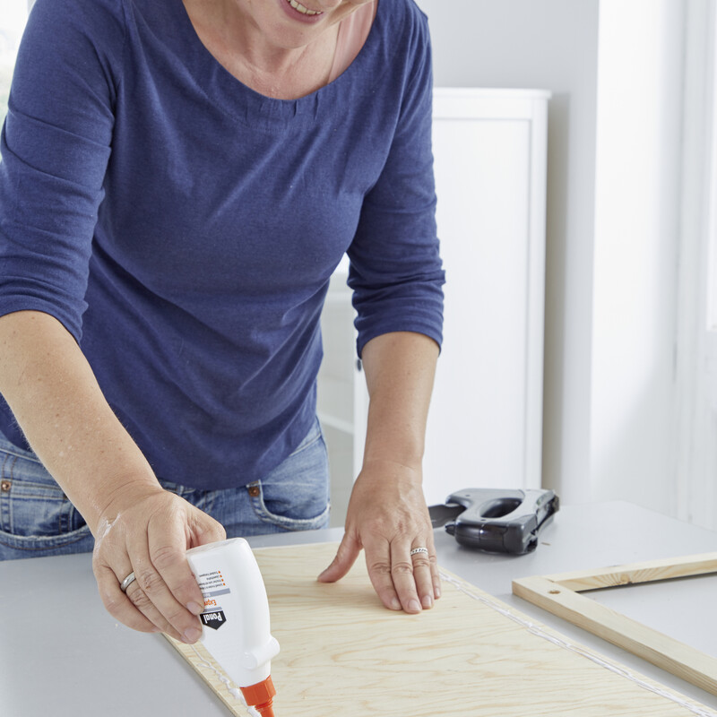 Eine Frau verteilt Leim auf einem Holzbrett