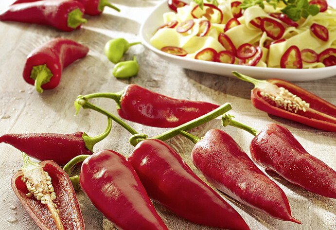 Rote Spitzpaprika liegen aufgereiht auf einem Tisch