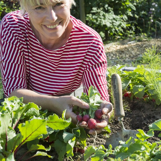 Frau befüllt Hochbeet mit Erde