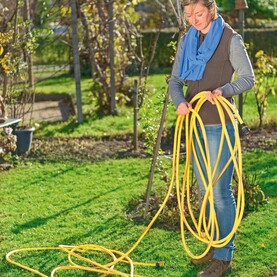 Frau rollt Gartenschlauch auf