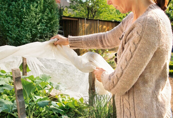 Frau deckt Hochbeet ab