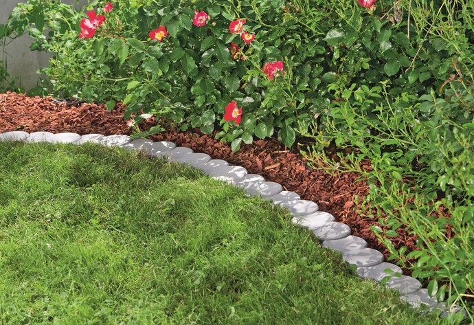 Palisaden-Randsteine als Grenze zwischen Blumenbeet und Rasen