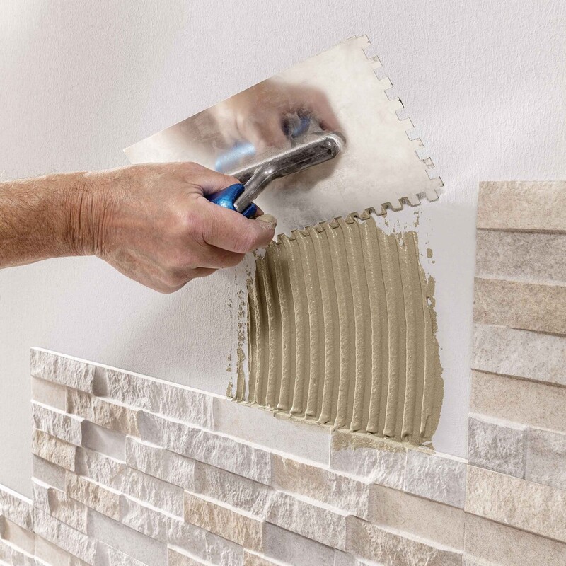 Kleber mit Kelle auf die Wand auftragen