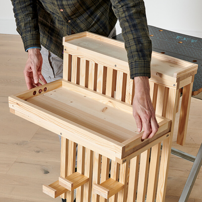 Mann stellt Holztablett auf Holzkonstruktion