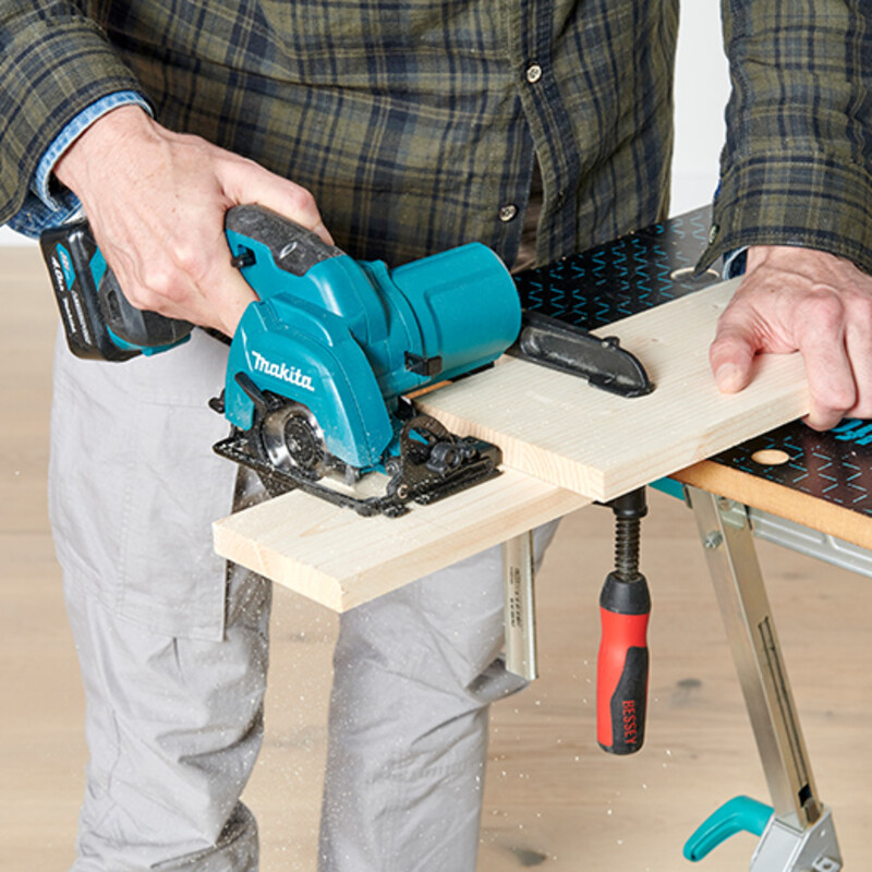 Mann bedient Handkreissäge und schneidet Holzbrett