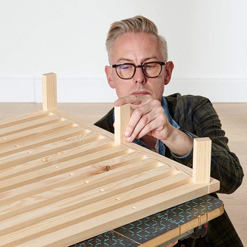 Mann mit Brille befestigt Leisten aus Holz
