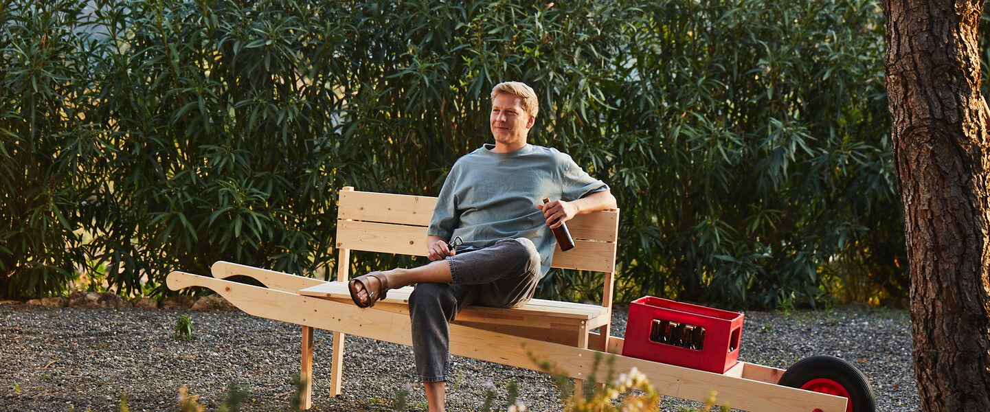 Mann sitzt auf der Bank zum Mitnehmen in der Sonne