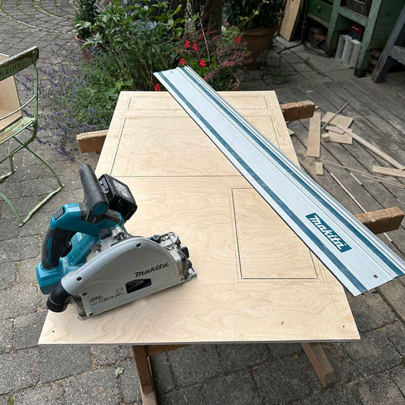 Säge auf Holzbrett, danben eine Führungsschiene