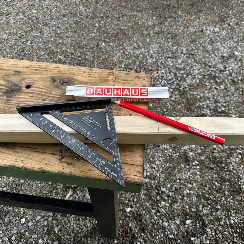 Messwinkel, Bleistift und Gliedermaßstab liegen auf Kantholz
