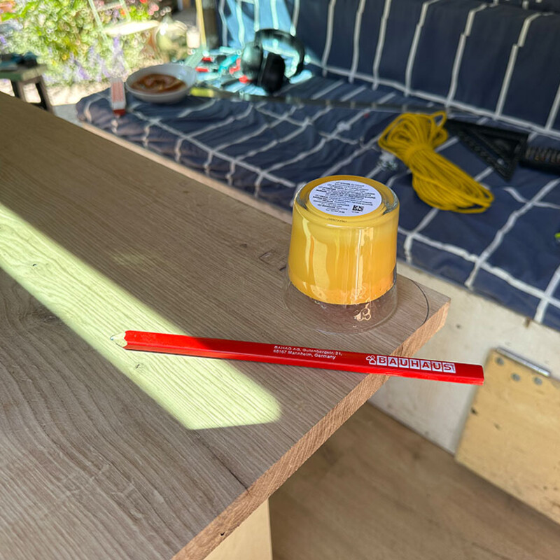Kerze steht umgedreht auf der Arbeitsplatte einer DIY-Camper-Küche, daneben liegt ein roter Bleistift