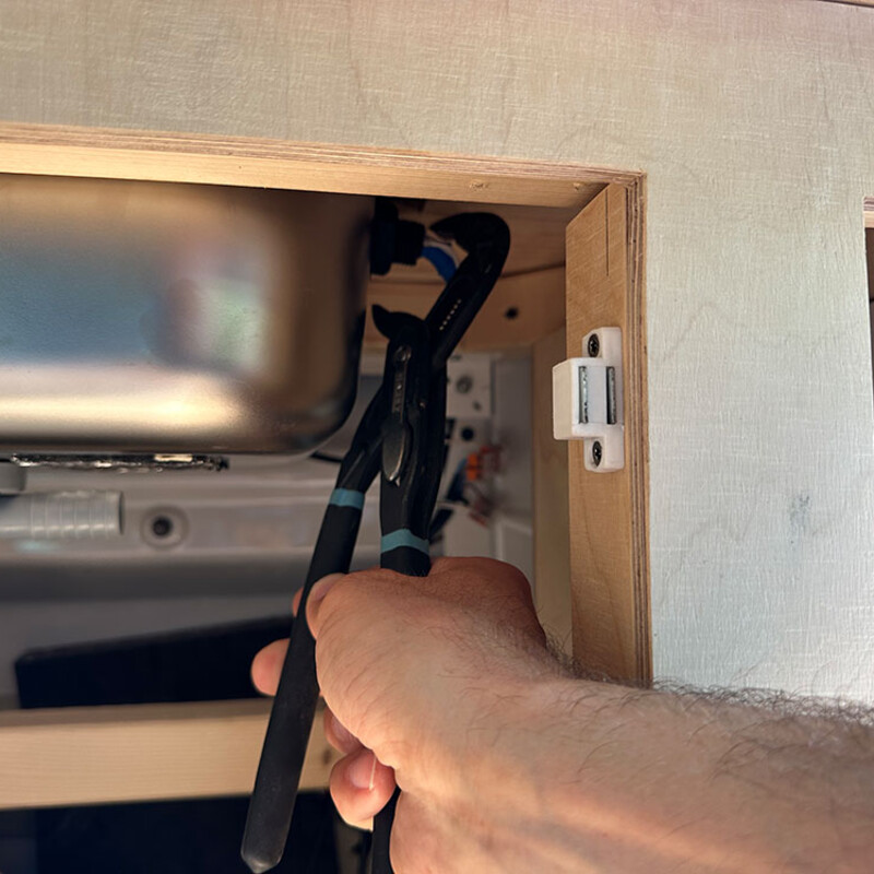 Spülbecken einer DIY-Camper-Küche wird mit Wasserpumpen-Zange montiert