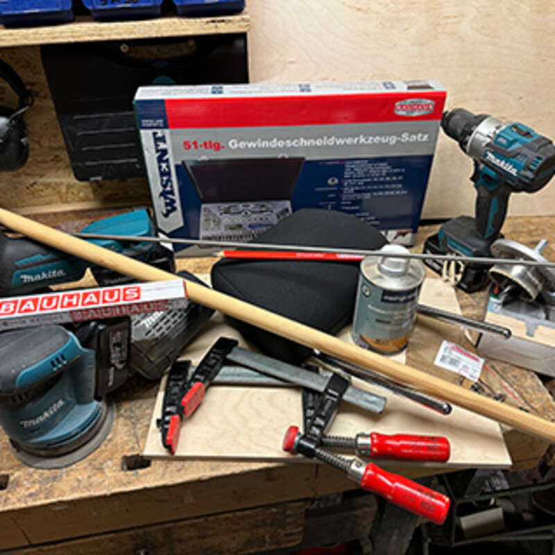 Werkzeug und Material für den Bau eines DIY-Camper-Regals liegen auf einer Werkbank