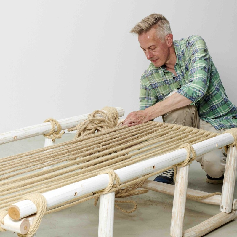 Mann spannt die Liegefläche eines Daybeds mit Seil