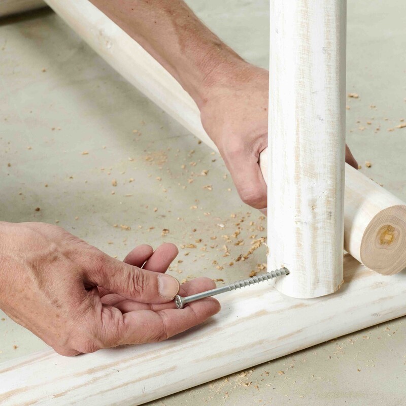 Hand steckt Schraube in Holz