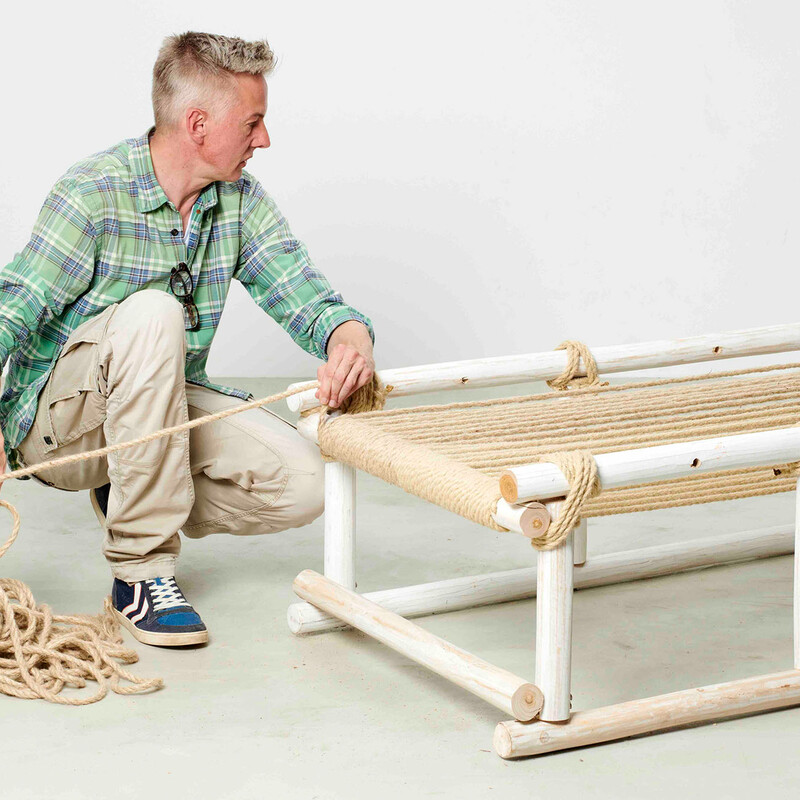 Mann sitzt neben selbstgebautem Daybed und konstruiert die Liegefläche aus Seil