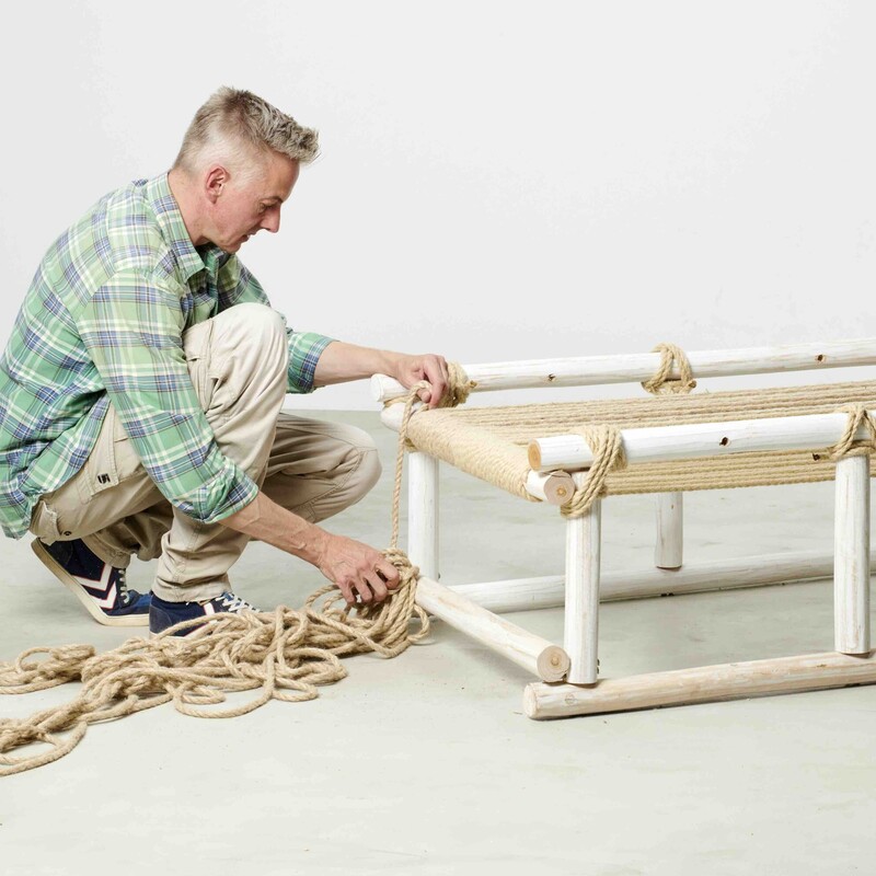 Mann baut Daybed aus Holz mit Liegefläche aus gespanntem Seil
