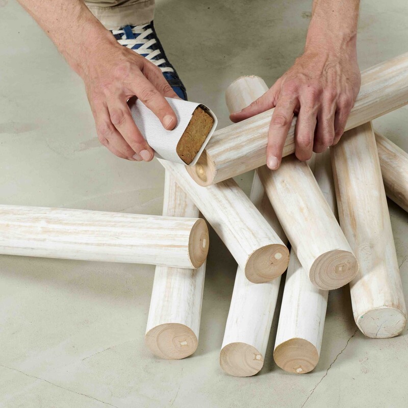 Mann schleift Holzstücke mit Schleifpapier von Hand