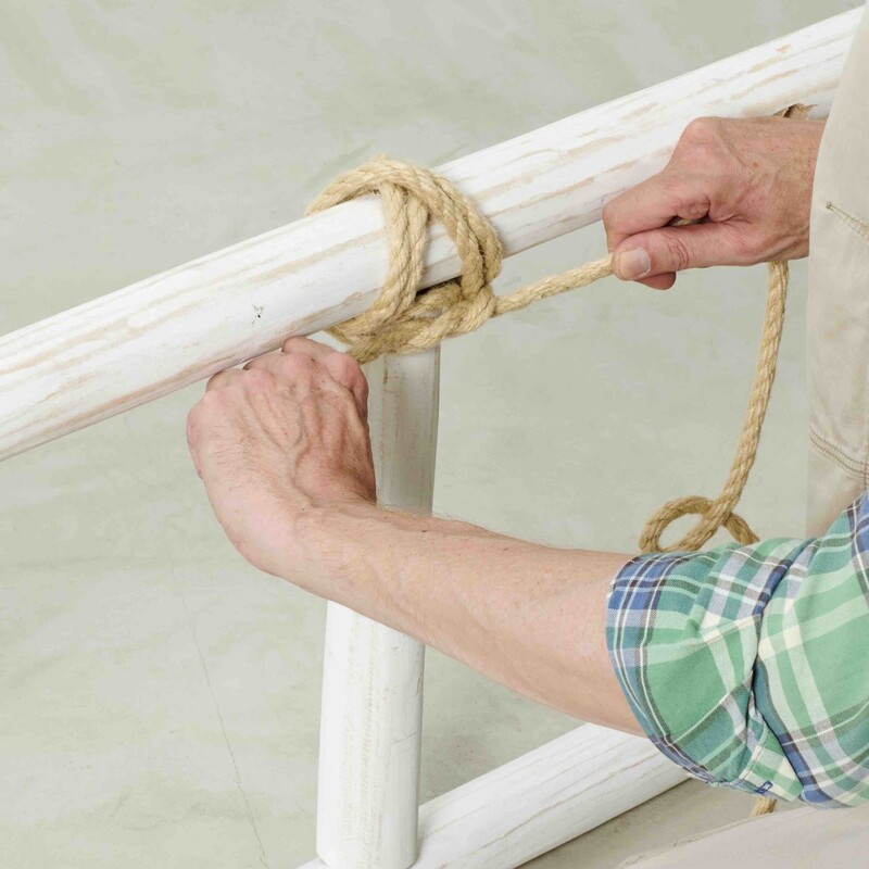 Mann umwickelt Holz mit Seil