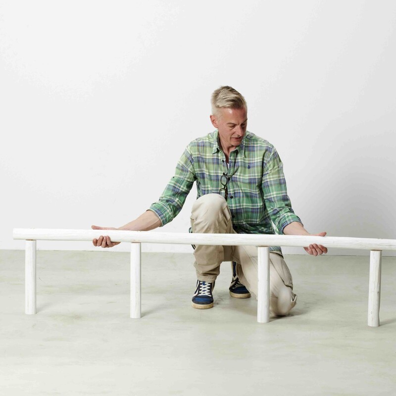 Mann konstruiert Daybed aus Teakstämmen
