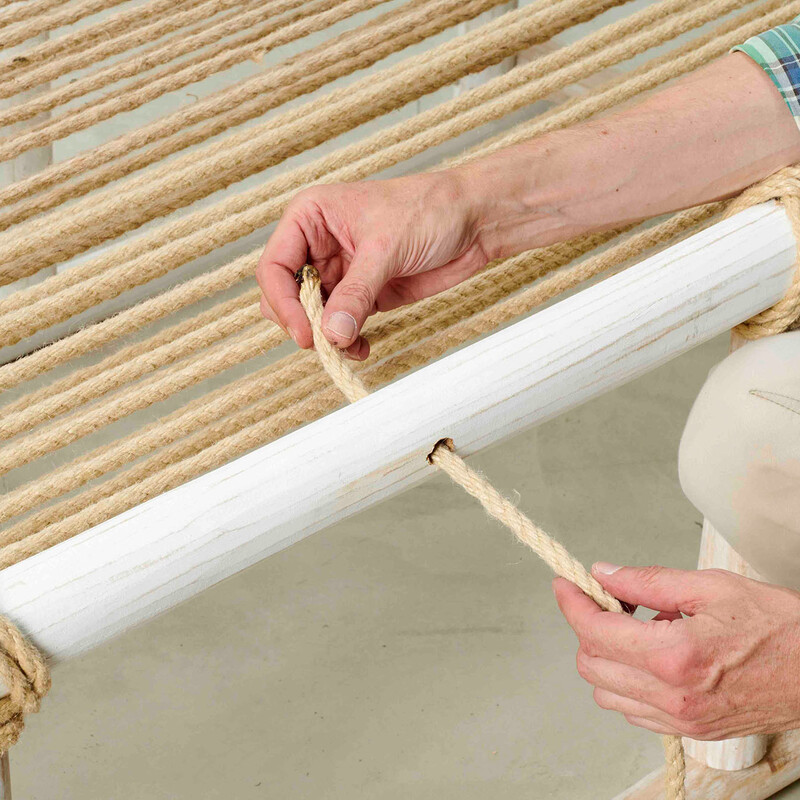 Mann führt Seil durch Loch in Holzstamm eines DIY Daybeds
