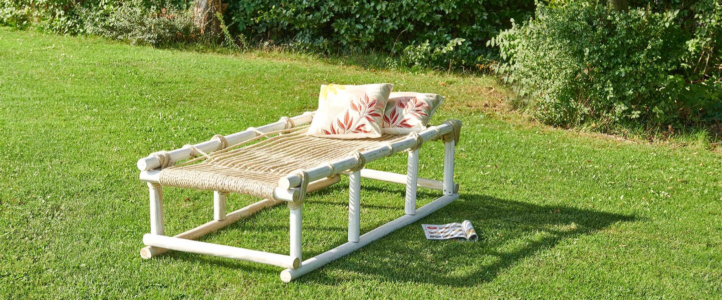 Selbstgebaute Liege aus Teakholz steht auf dem Rasen im Garten