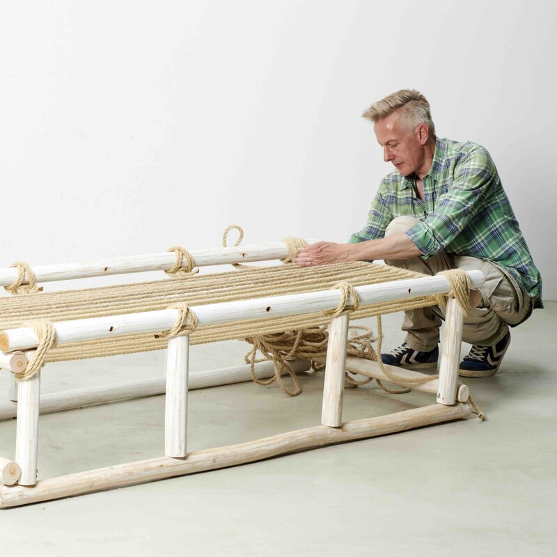 Mann sitzt neben selbstgebautem Daybed und konstruiert die Liegefläche aus Seil