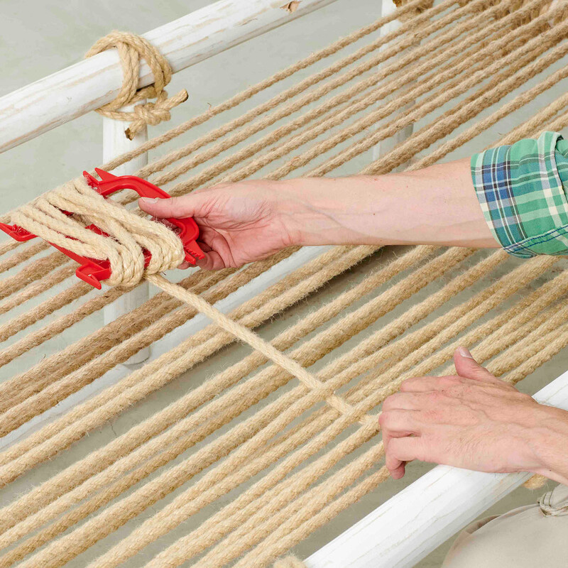 Mann fädelt Seil für die Liegefläche eines selbstgebauten Daybeds aus Teakholz