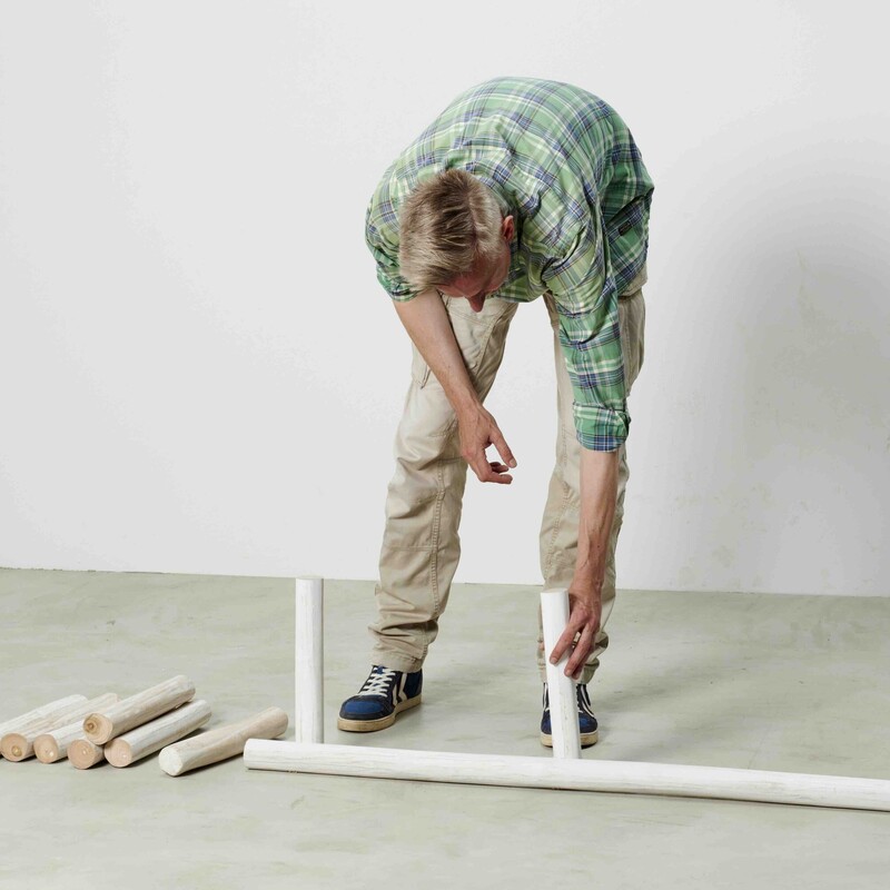 Mann konstruiert Daybed aus Teakstämmen