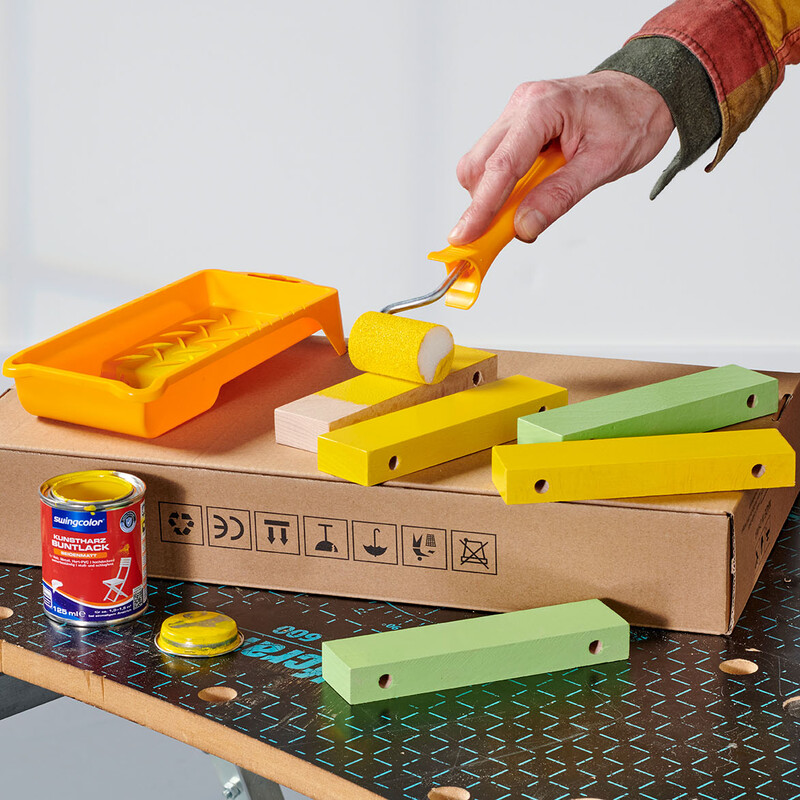 Mann lackiert Leistenzuschnitte mit gelbem Buntlack von Swingcolor