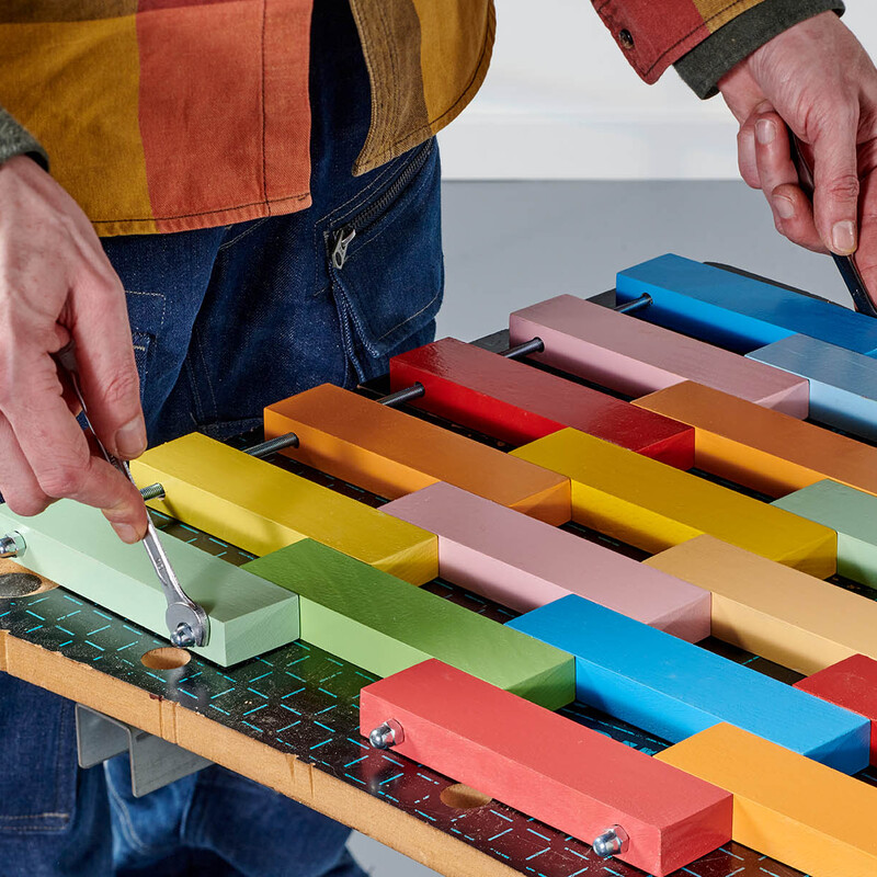 Man schraubt Hutmuttern an einer DIY-Fußmatte aus Holz fest