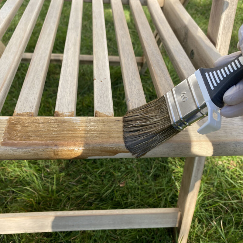 Mit Pinsel &Ouml;l auf Gartenstuhl auftragen