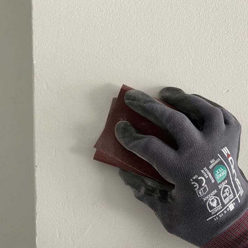 Wand wird mit Schleifpapier angeschliffen