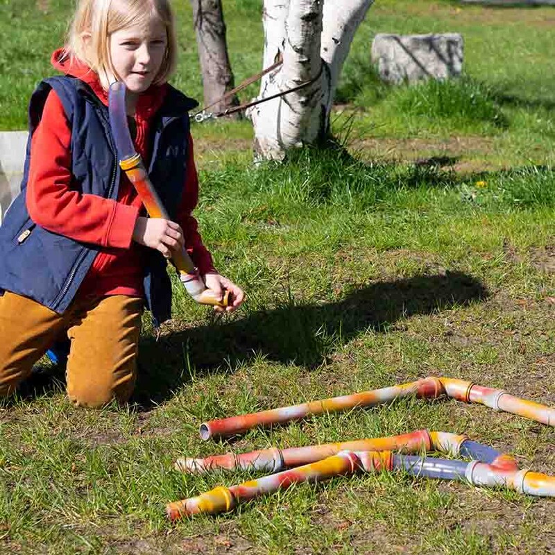 Kind steckt selbstgemachte Kugelbahn im Park zusammen