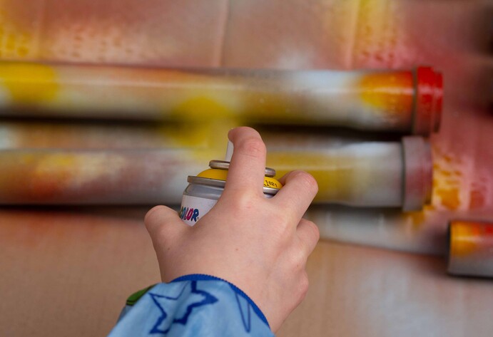 Kind sprüht Kunststoffrohre für DIY-Kugelbahn