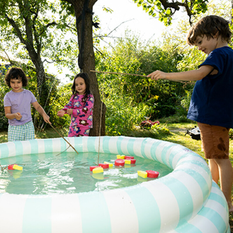 Kinder stehen mit selbst gebasteltem Angelspiel am Planschbecken im Garten