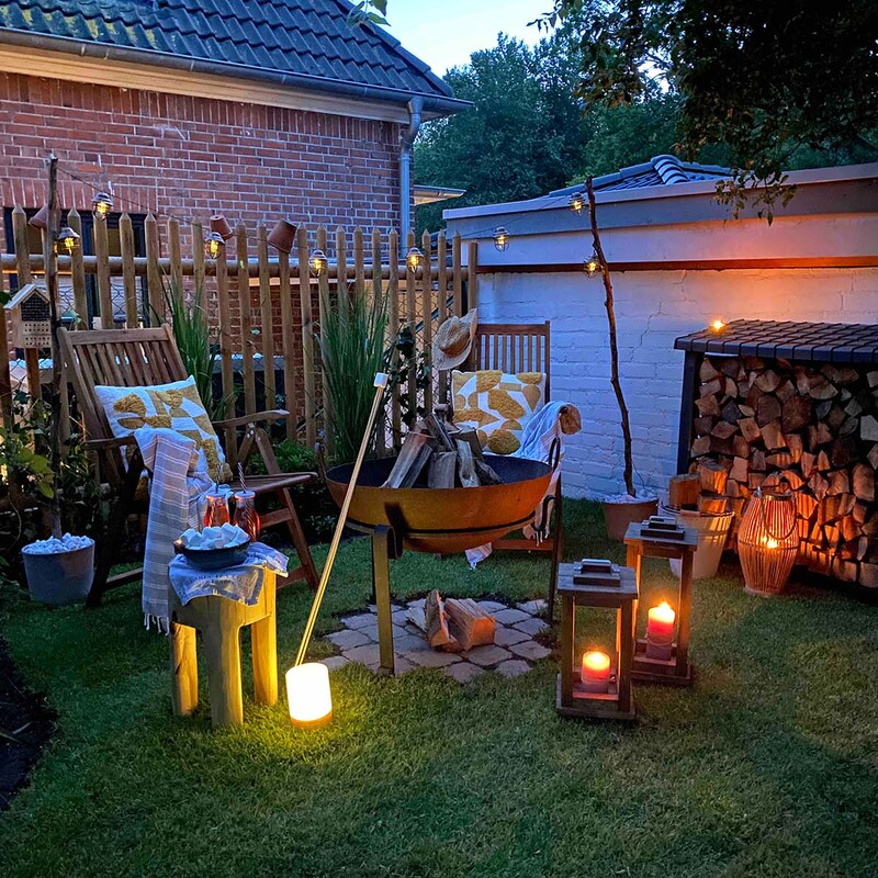 Feuerschale im Garten bei Nacht mit leuchtender Lichterkette