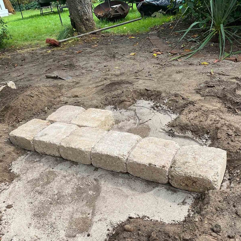 Mauersteine auf Sandfläche im Garten