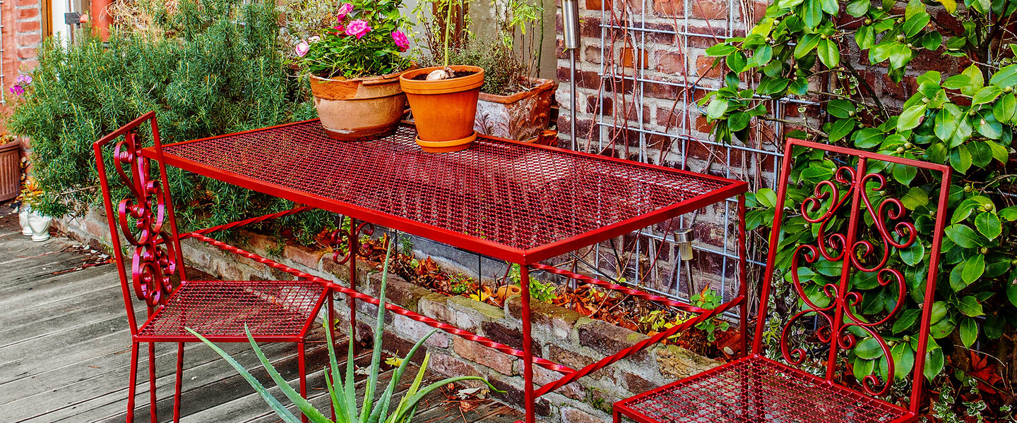 rote Gartenst&uuml;hle und roter Tisch auf Terrasse
