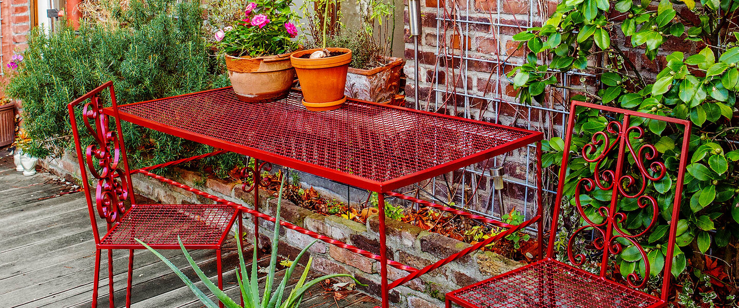 rote Gartenstühle und roter Tisch auf Terrasse