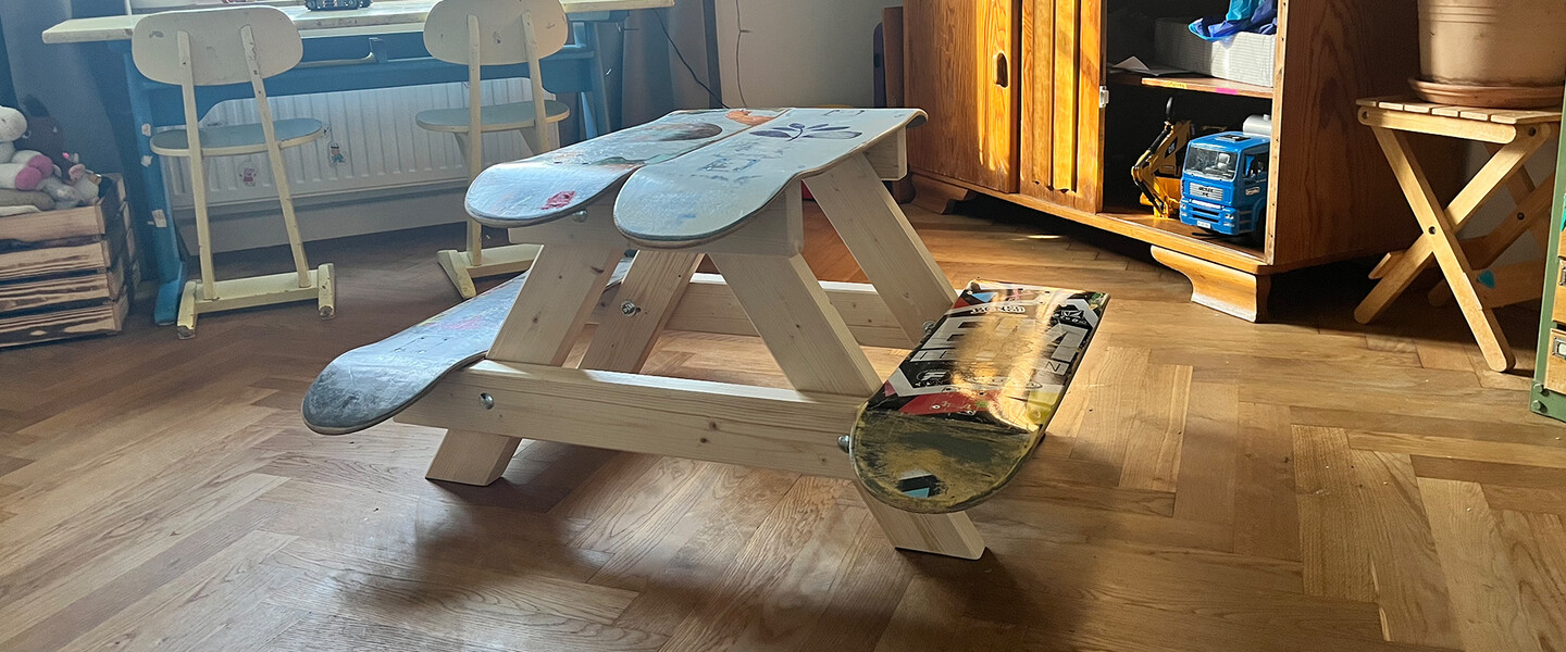Picknick-Tisch für Kinder aus 4 Skateboards auf Dielenbdoen, im Hintergrund ein Kinderschreibtisch und ein Schrank mit Spielzeug