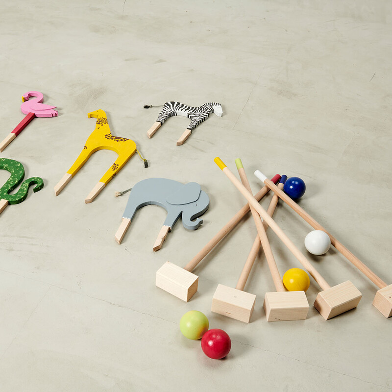 Selbstgemachte Tierfiguren für Krocket liegen neben Schlägern und bunt lackierten Kugeln aus Holz