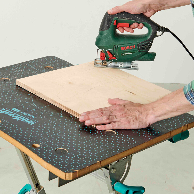 Mann schneidet Holzstück mit Stichsäge