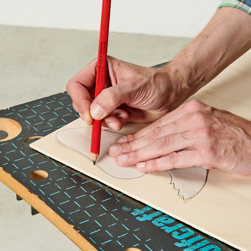 Hand zeichnet Umriss einer Tierfigur mit Bleistift auf Holz
