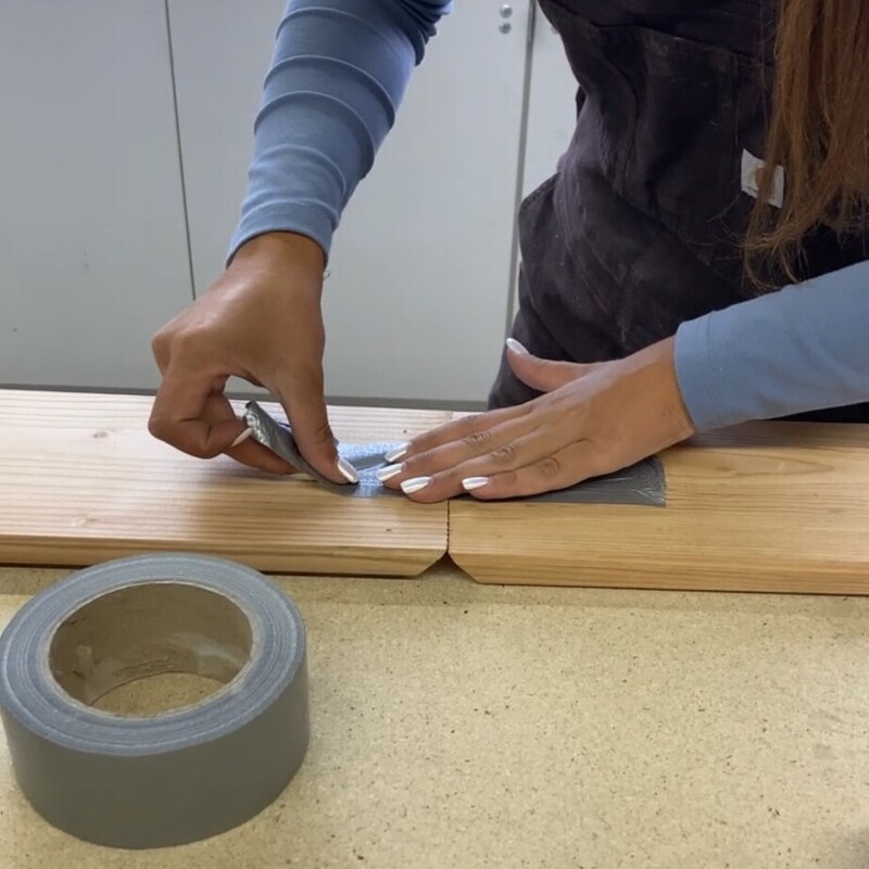 Frau befestigt Gaffa-Tape an Holzbrettern