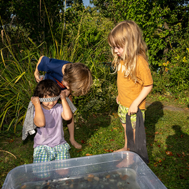 Kinder im Garten legen Augenbinde an