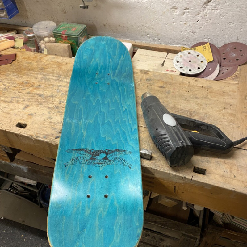 Skateboarddeck ohne Griptape neben Heißluftfön