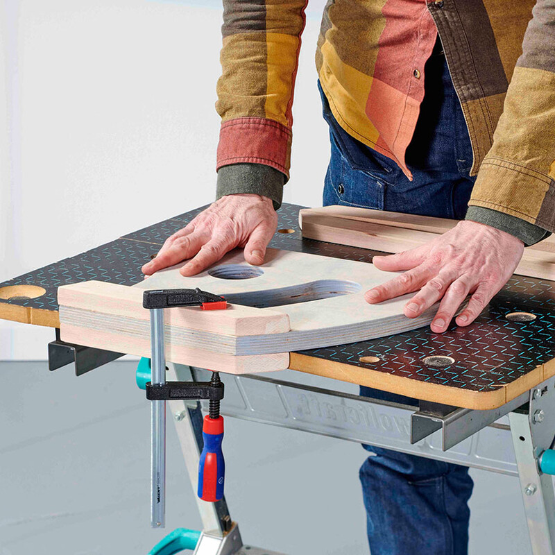 Mann befestigt Holzteile mit Schraubzwingen am Werktisch