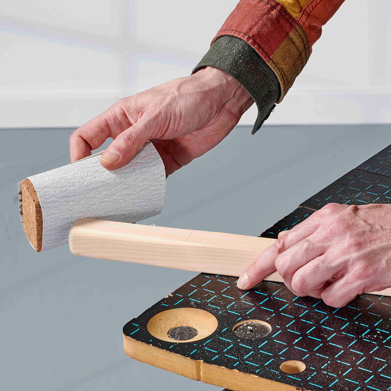 Mann schleift Holzstück mit Schleifpapier